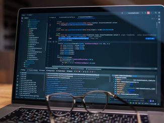 Computer screen with code and glasses on keyboard