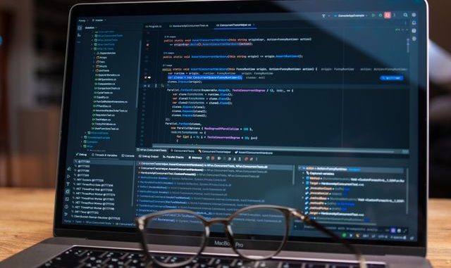 Computer screen with code and glasses on keyboard