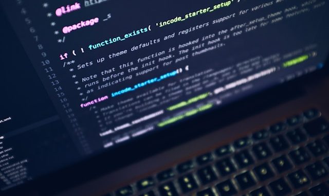 Programming code on screen of black computer with keyboard